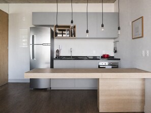 Una cocina moderna con una isla central, electrodomésticos de acero inoxidable e iluminación colgante.