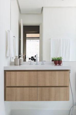 Un baño moderno con tocador blanco, dos lavamanos, un espejo y vistas al exterior.