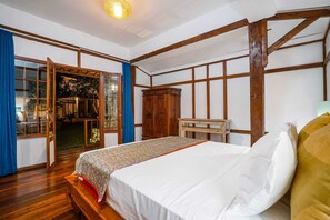 Una habitación con cama, vigas de madera, un armario y un escritorio.