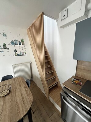 Une cuisine moderne avec un escalier en bois, une table à manger et un réfrigérateur.