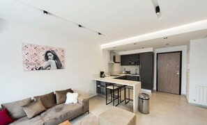 Un appartement moderne comprenant un coin cuisine, un canapé, une table basse et une poubelle.