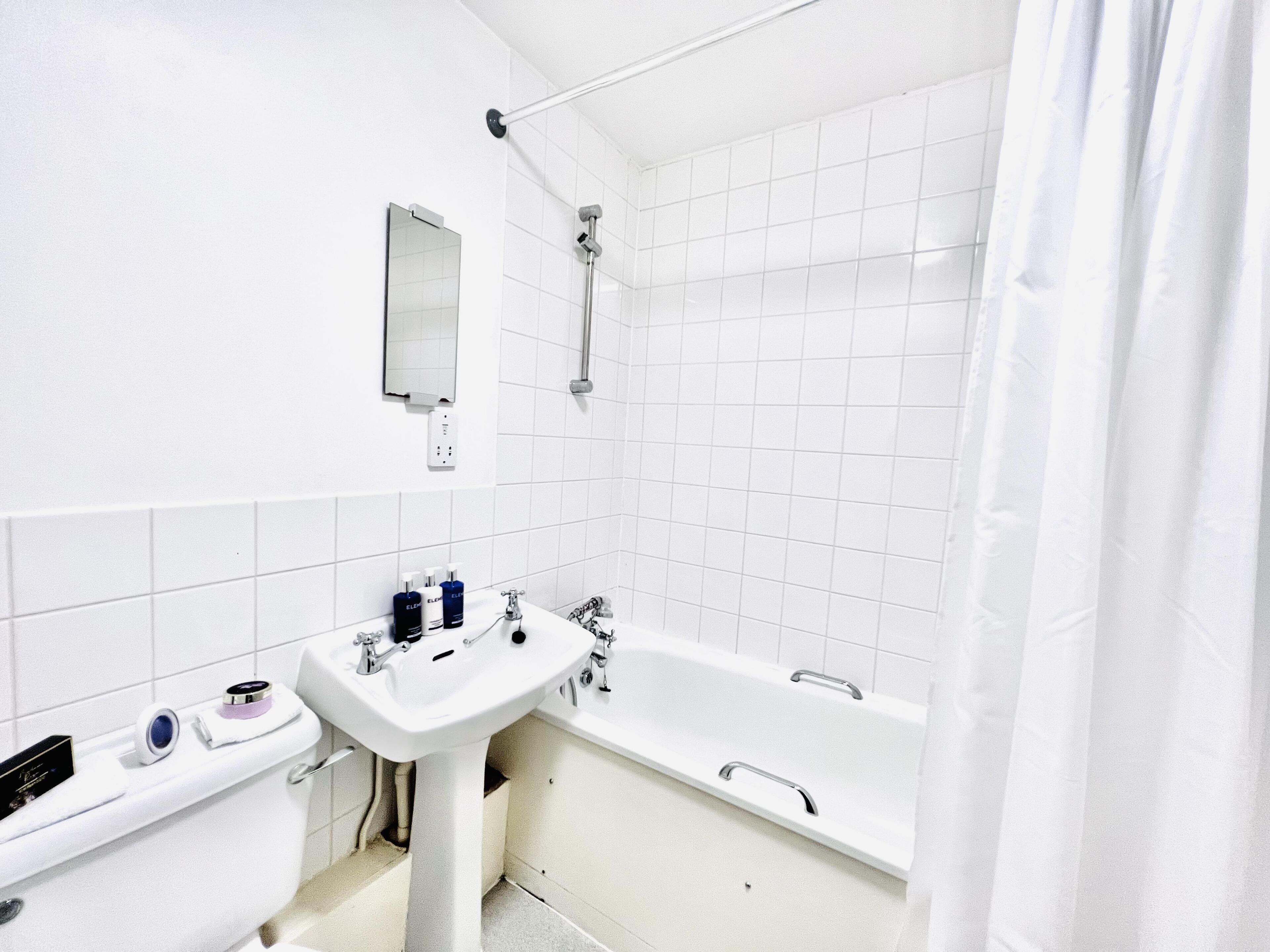 A modern bathroom with a white sink, a bathtub, and a shower.