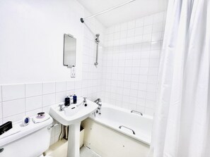 Une salle de bain moderne avec un lavabo blanc, une baignoire et une douche.