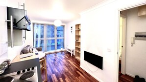 A modern kitchen with a stove, a dining table, and a window with blinds. - Lovely 1-bed Apartment in London by the Harbour (London)