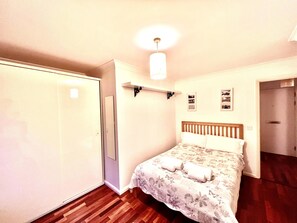 Une chambre à coucher comprenant un lit, une armoire, un luminaire suspendu et une porte.