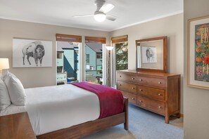 Een slaapkamer met een bed, een dressoir en kunstwerken aan de muur.