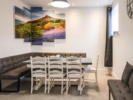 Uma área de jantar moderna com um sofá marrom, cadeiras brancas e uma mesa.