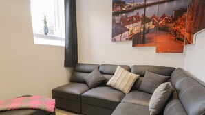 Una sala de estar moderna con un sofá modular, una mesita y una ventana con vistas a un pueblo costero.