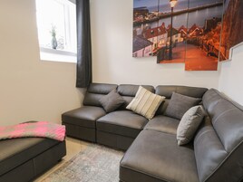 Uma sala de estar moderna com um sofá seccional, uma mesinha e uma janela com vista para uma cidade costeira.