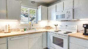 Una cucina moderna con mobili bianchi, un forno a microonde integrato, un piano cottura e una lavastoviglie.