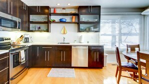 Una cocina moderna con armarios oscuros, un microondas de acero inoxidable y un lavavajillas.