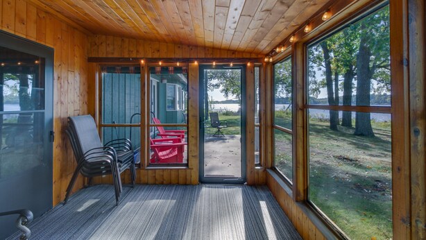 Una cabaña con interior de madera, ventanas amplias y vistas al exterior.