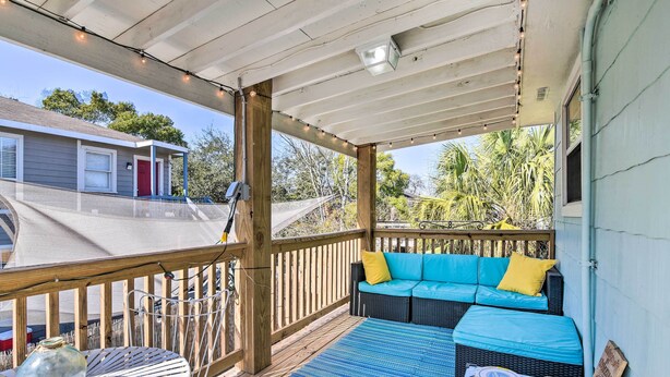 A covered outdoor deck with a blue sofa, a round table, and a tiki torch. - Galveston Retreat w/ Backyard & Patio! (Galveston)