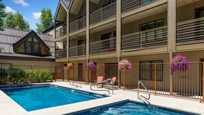 A swimming pool with a hot tub, surrounded by a building with balconies and railings. - Chic, Modern Walk Anywhere @ Viking Lodge 206 1 Bedroom Condo by RedAwning (Telluride)