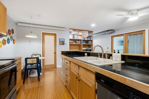 Una cocina moderna con lavavajillas, pileta doble y un comedor con mesa y sillas.