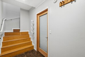 A staircase with wooden steps and white handrails, leading to a door with a glass panel and a wooden frame.