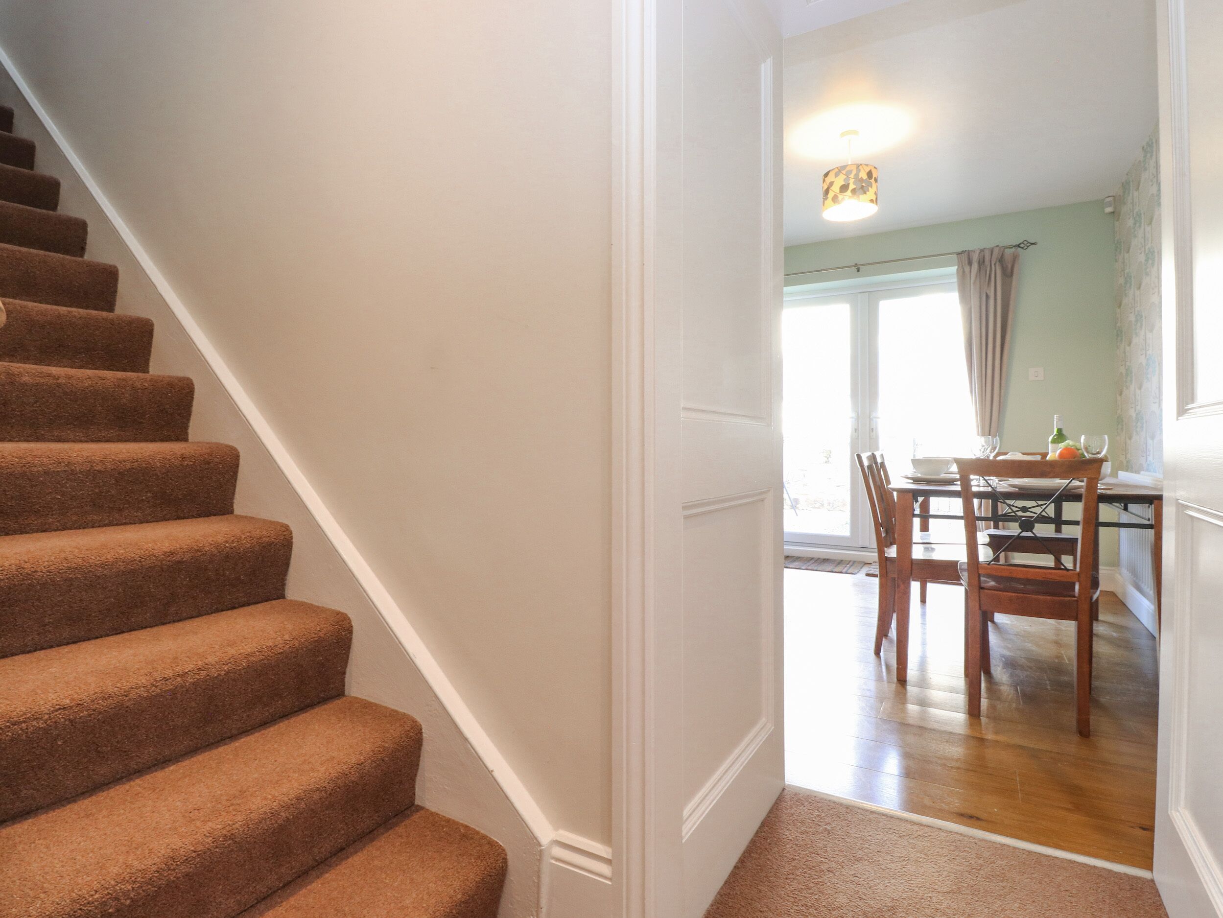 A staircase leading to a dining area with a table and chairs.