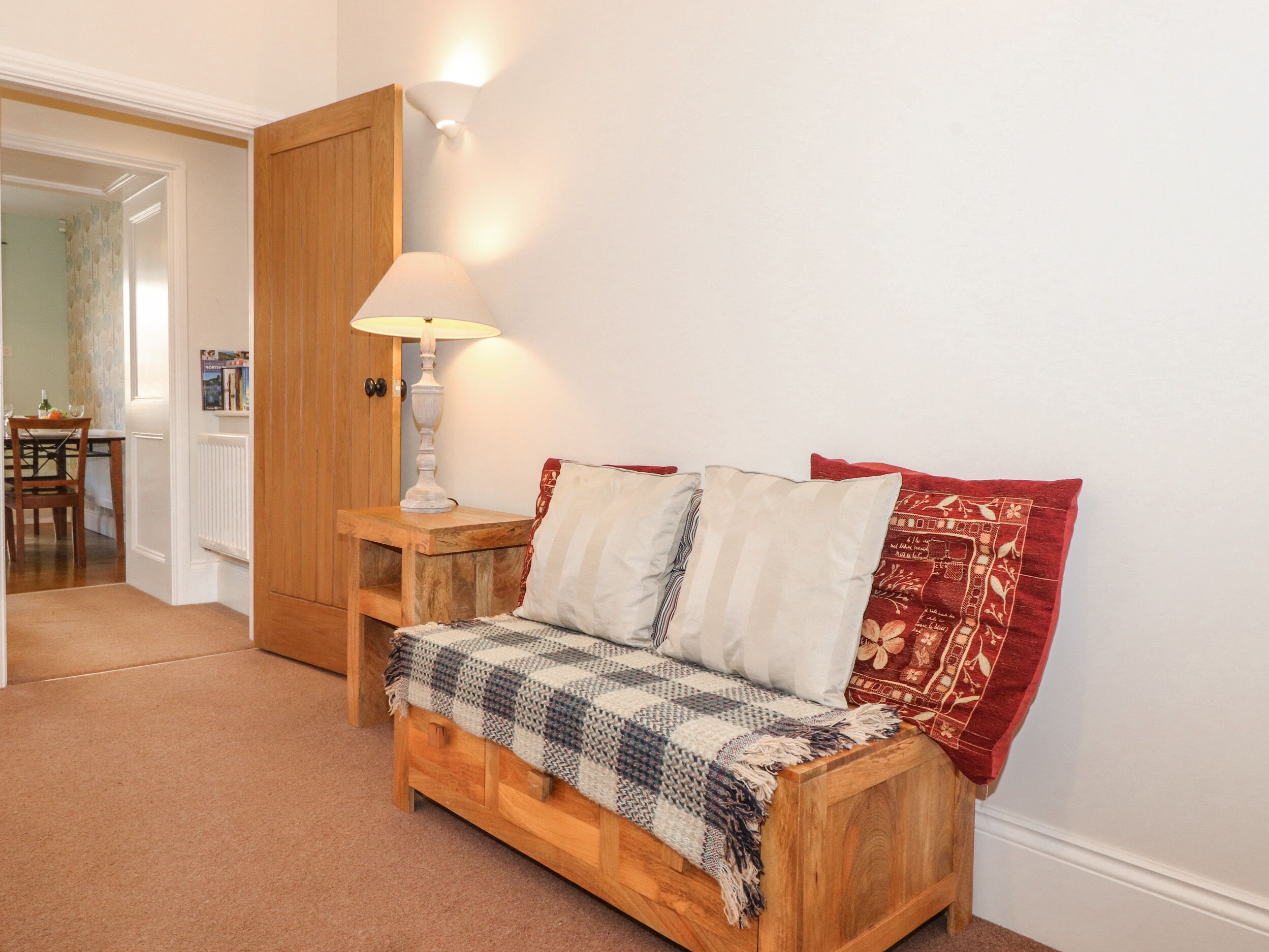 A cozy room with a wooden sofa, a lamp, and a patterned throw blanket.