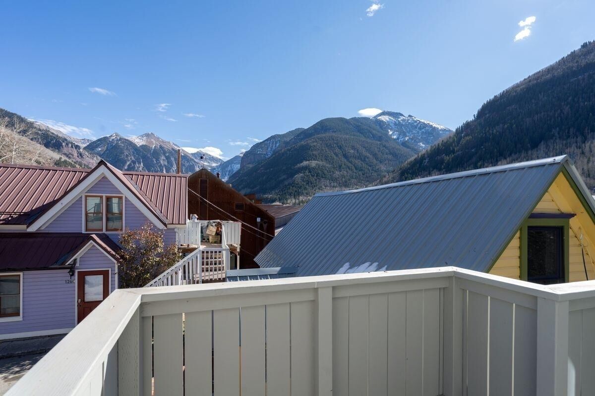 A residential area with houses, a wooden deck, and mountains in the background.