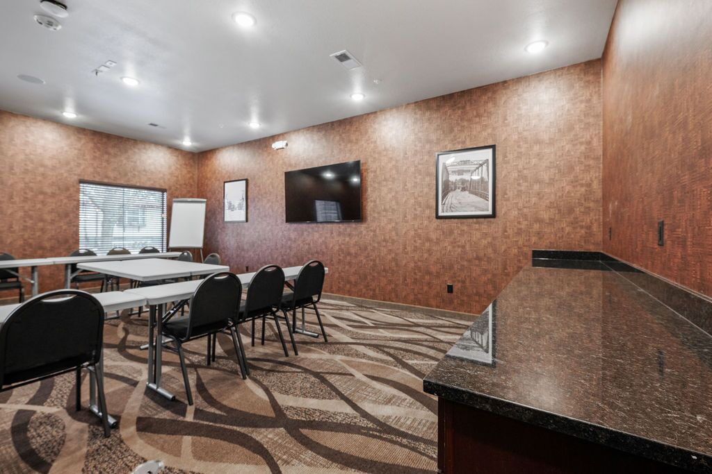 A conference room with a long table, chairs, a whiteboard, and a television.