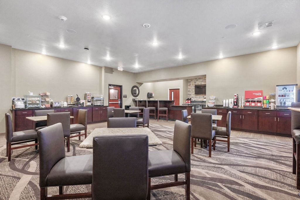 A hotel lobby with a reception desk, seating area, and a kitchenette.