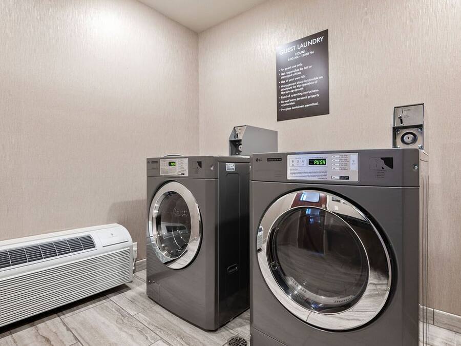 A hotel laundry room with two front-loading washers and a wall-mounted dryer.