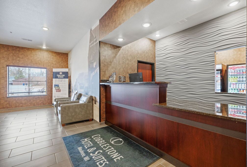 A hotel reception area with a reception desk, a waiting area with sofas, a patterned wall, and a vending machine.