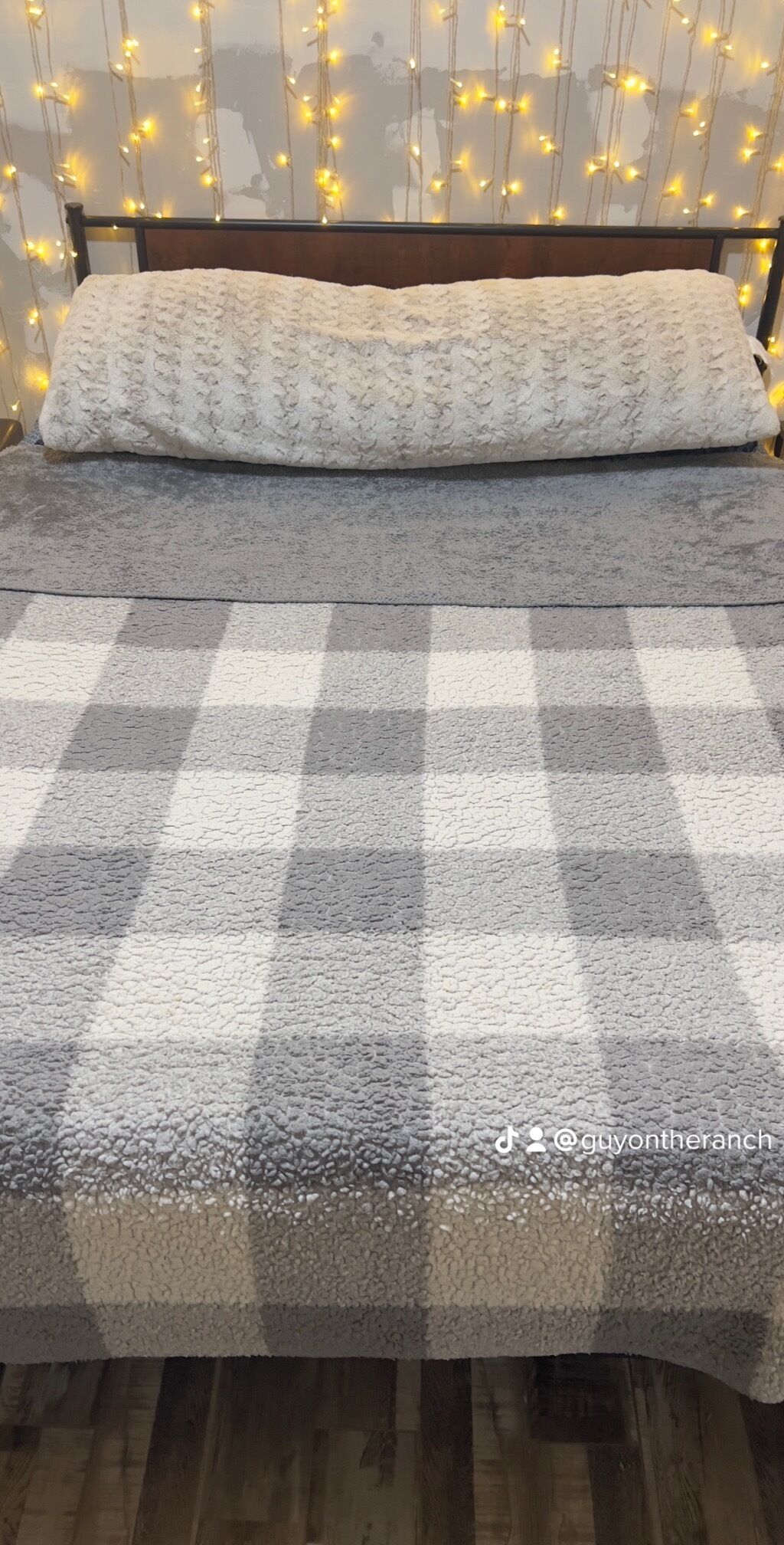A bed with a checkered blanket, a pillow, and a headboard.