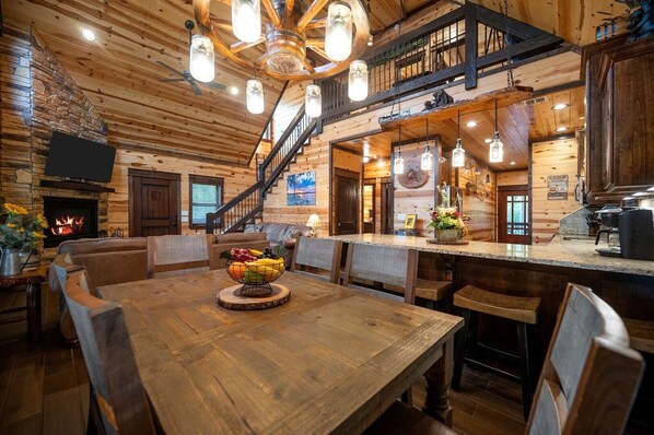 Un intérieur en bois comprenant un coin repas, une cheminée et un escalier menant à un niveau supérieur.