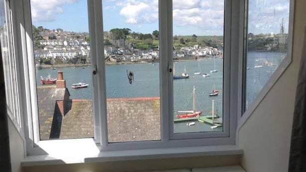 A room with a large bay window overlooking a harbor with boats and buildings. - Newly Refurbished 7-bed Cottage in Polruan, Fowey (Fowey)