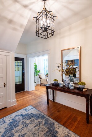 Enter a stylish space with a console table, mirror, and chandelier.