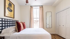 A bedroom with a bed, a headboard, a window with curtains, a mirror, and a wardrobe. - EH Taylor Suite, The Woodford Hotel (Versailles)