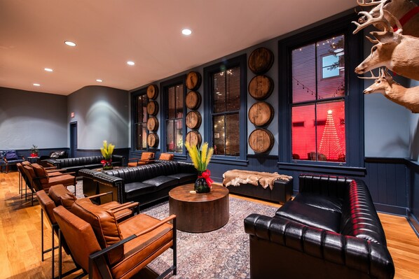 Eine moderne Lounge mit Ledersofas, einem runden Couchtisch und einer Wand, die mit Holzbottichen und Hirschgeweihen dekoriert ist.