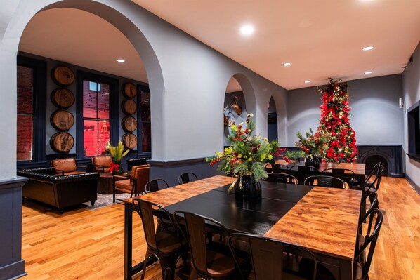 A dining area with a wooden table and chairs, a Christmas tree, and a fireplace. - The Woodford Hotel — Private 8-Suite Buyout | Sleeps 24 (Versailles)