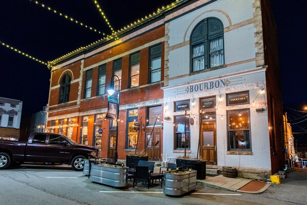 Een historisch gebouw met een bar genaamd 'BOURBON' op de begane grond, met terras en een klassiek bakstenen gevel.