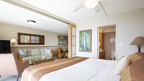 Een hotelkamer met een bed, een bank, een eettafel en een schilderij.
