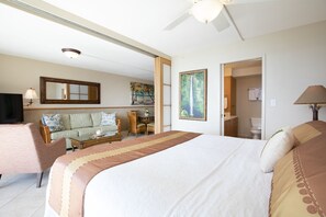 Een hotelkamer met een bed, een bank, een eettafel en een schilderij.