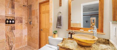 Baño con ducha, inodoro, lavamanos y espejo.