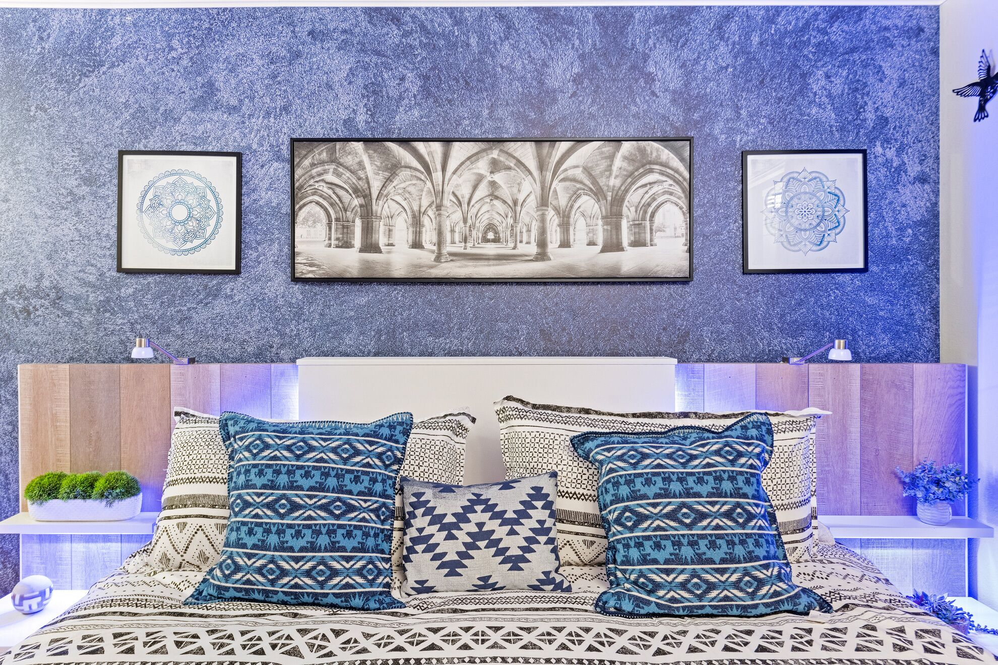 A bedroom with a bed, pillows, and wall art.