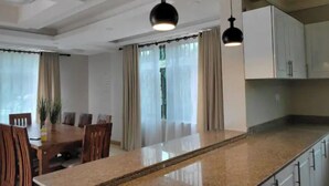 A modern kitchen with a granite countertop, white cabinets, and pendant lighting. - Home away from Home -Beautiful and Spacious House (katabi, Entebbe)