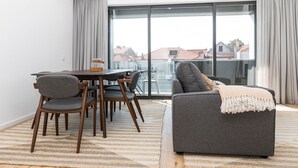 Una sala de estar moderna con comedor, ventanas amplias y vista a edificios.