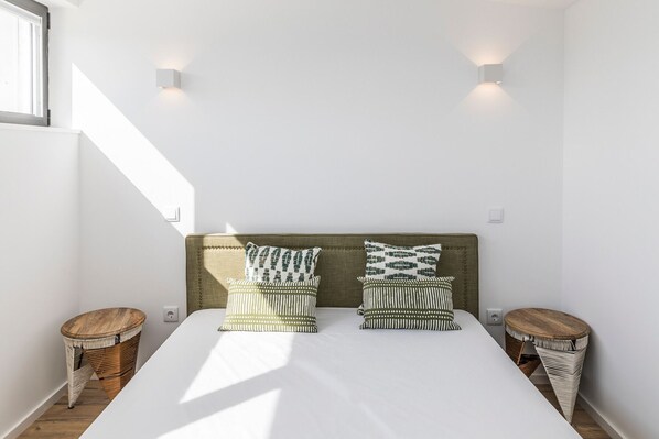 A bedroom with a bed, two wall-mounted lights, and two side tables.