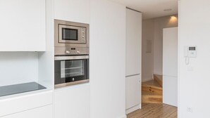 Una cocina moderna con electrodomésticos integrados, piso de madera e interior blanco.