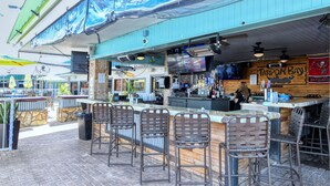 An outdoor bar area with a counter, bar stools, and a sign reading "Tarpon Bay." - ALL-NEW Waterfront Room, Heated Pool, Tiki Bar/Grill (Sarasota)