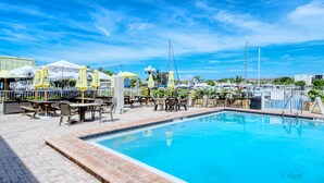 A swimming pool with lounge chairs and umbrellas, surrounded by a fence and a view of the marina. - ALL-NEW Waterfront Room, Heated Pool, Tiki Bar/Grill (Sarasota)