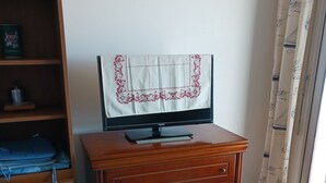 Una habitación con un armario de madera, un televisor encima y suelo de baldosas.