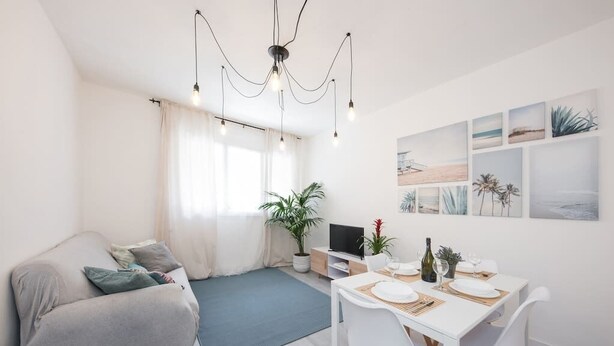 A modern living room with a sofa, dining table, and artwork on the wall.
