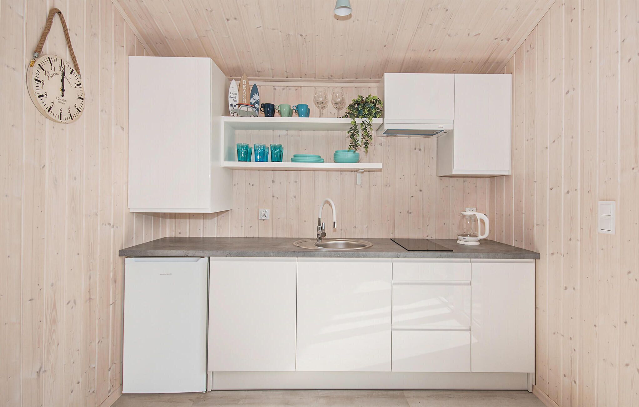 Una cocina compacta con gabinetes blancos, un lavamanos y una encimera.