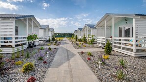 A row of white cabins with a gravel pathway leading to a grassy area. - Stunning home in Darlowo with WiFi (Darlowo)