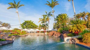 A pool area with palm trees, a waterfall feature, and white umbrellas. - Waikomo Stream Villas 530 – A/C, 2 Bedroom, PBAC Membership (Koloa)